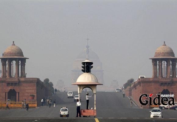 印度新德里，总统府前的交警在浓雾中指挥交通。